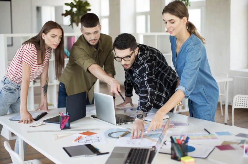 Marketing team discussing travel campaign ideas around a laptop