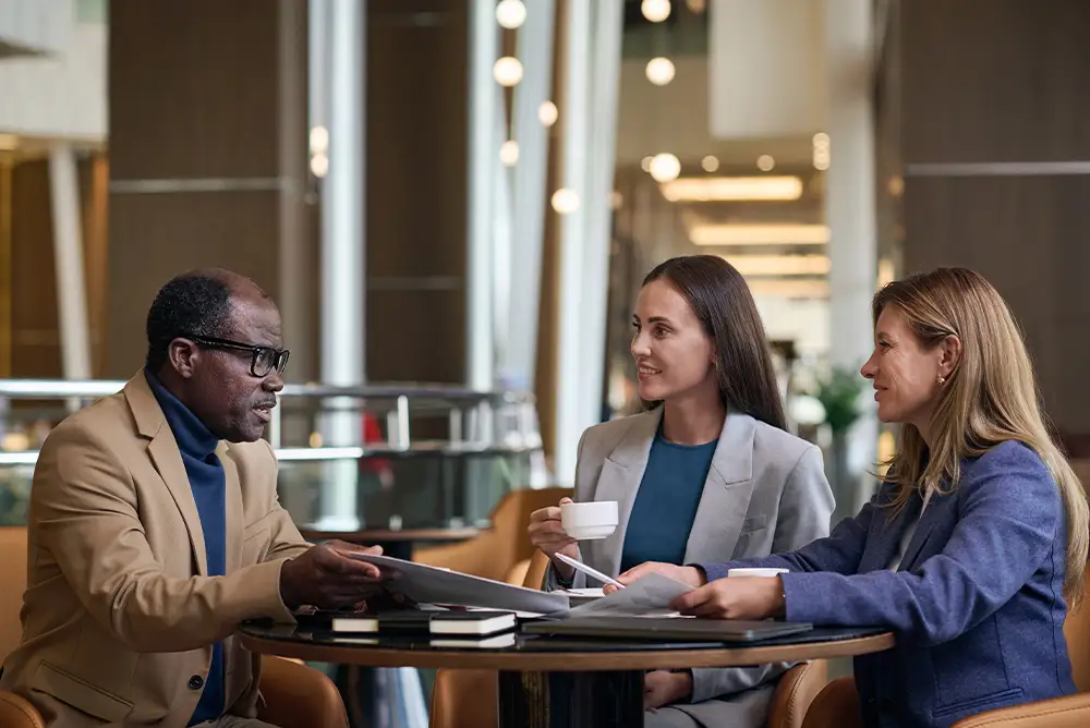 A real estate agent outlining business goals and marketing ideas in a notebook next to a coffee cup and phone.